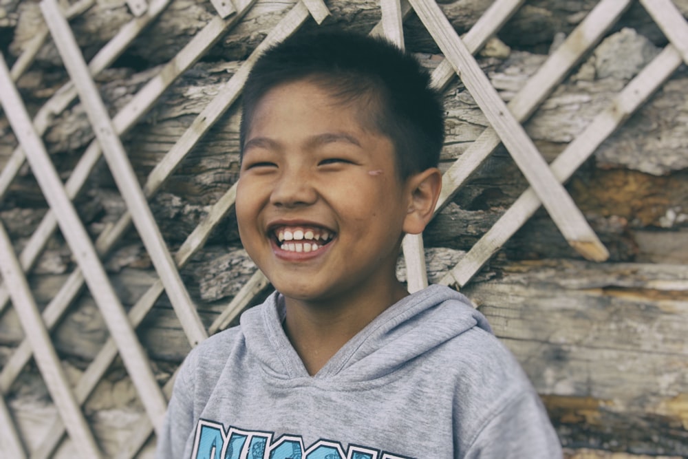 Chico sonriente con sudadera con capucha gris y azul