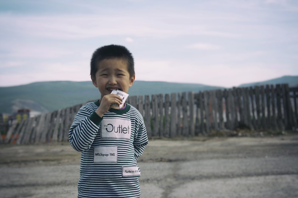 boy in black and white striped long sleeve shirt drinking from white plastic cup