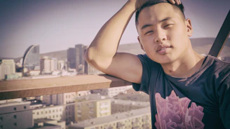 Model leaning against a subway railing wearing a loose, graphic tee with urban skyline prints.