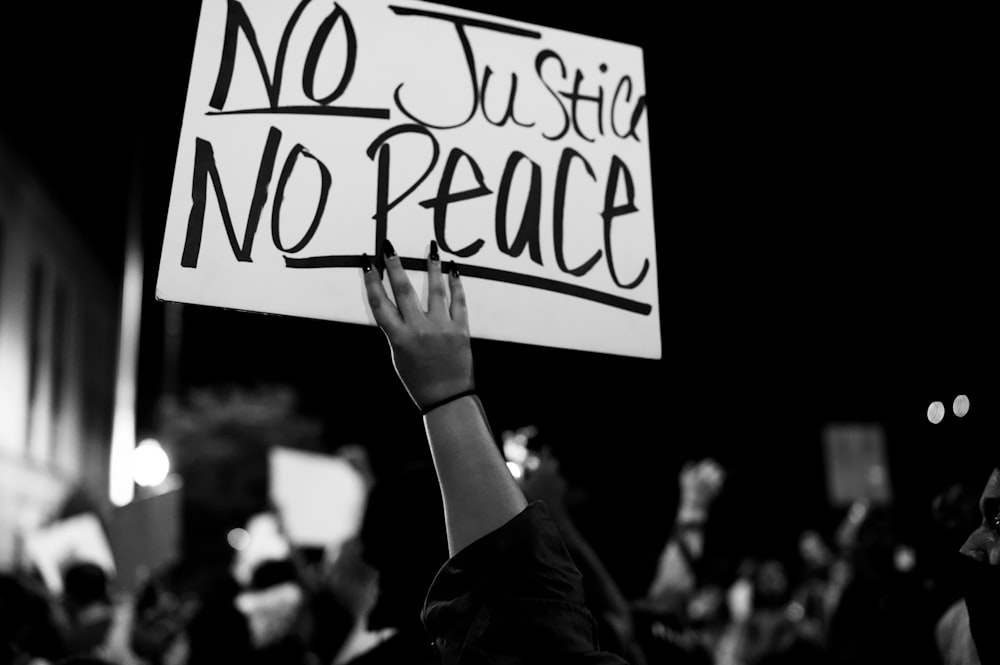 grayscale photo of person holding white and black love is love print signage