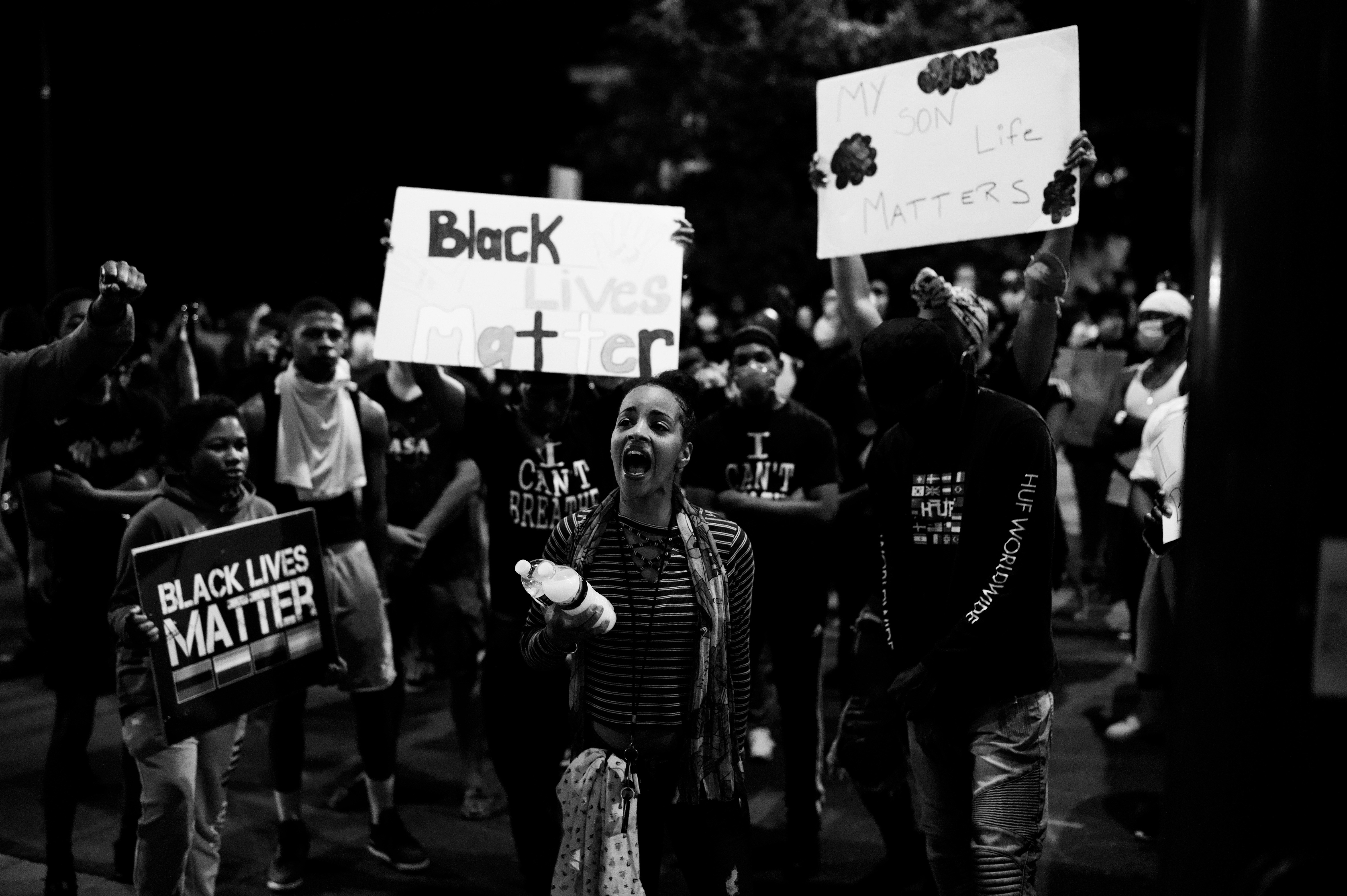 grayscale-photo-of-man-in-black-jacket-holding-white-and-black-signage