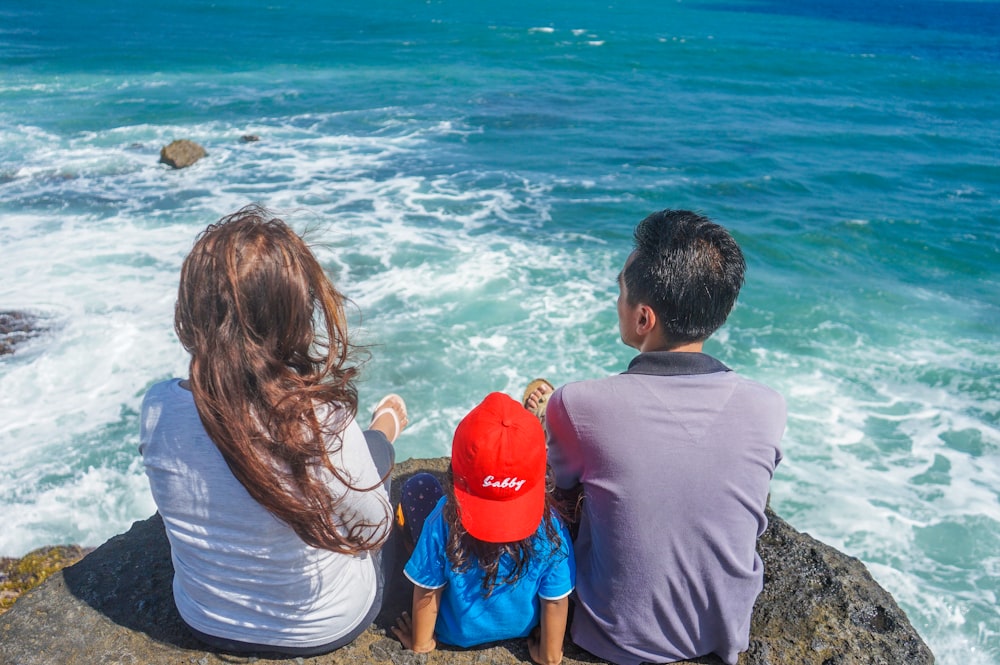 man and woman sitting on rock near body of water during daytime