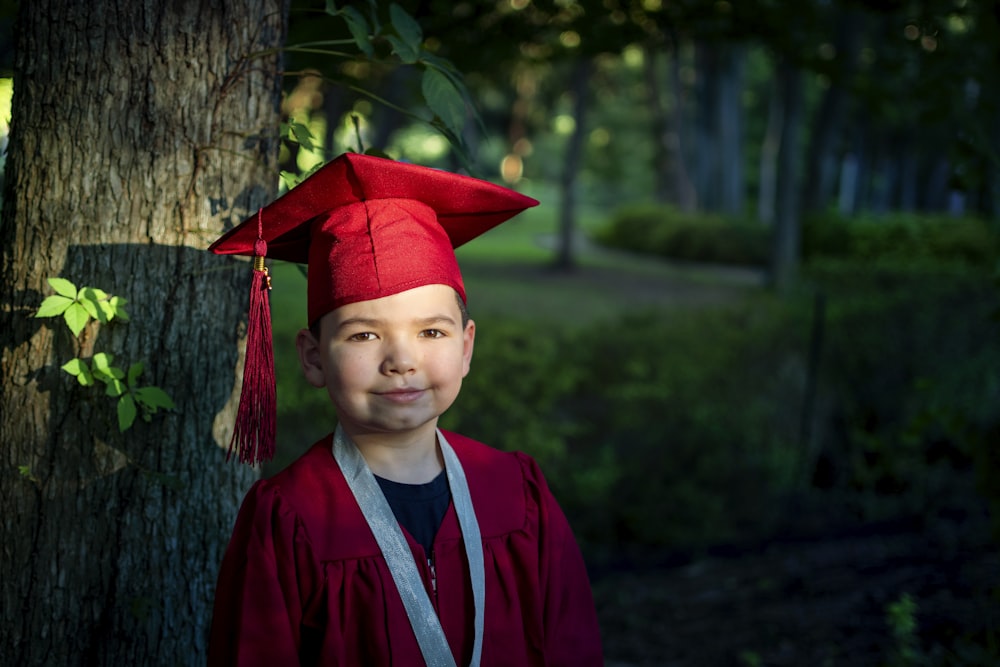 Junge in blauer akademischer Kleidung und rotem akademischen Hut