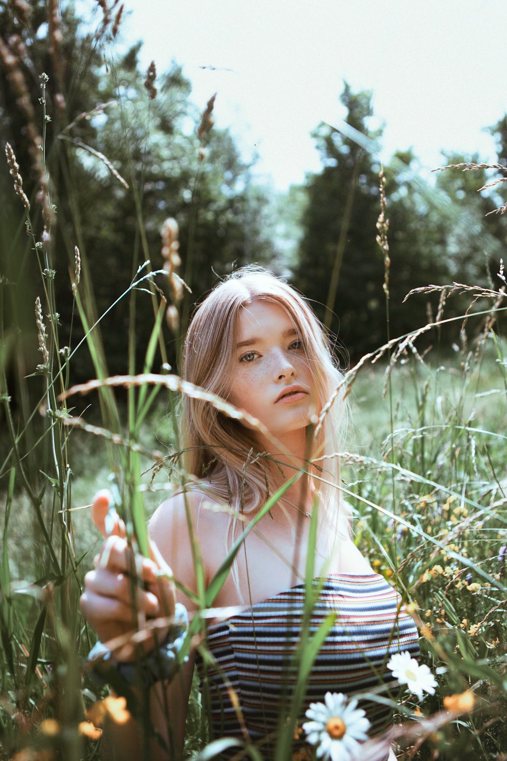 woman in white and black stripe tank top standing on green grass field during daytime