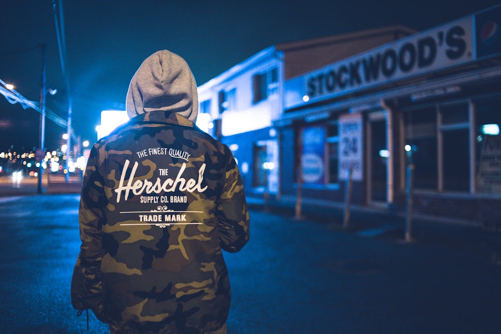 person in brown and black camouflage hoodie standing on street during night time