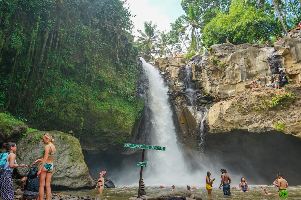 Persone in piedi su roccia marrone vicino a cascate durante il giorno