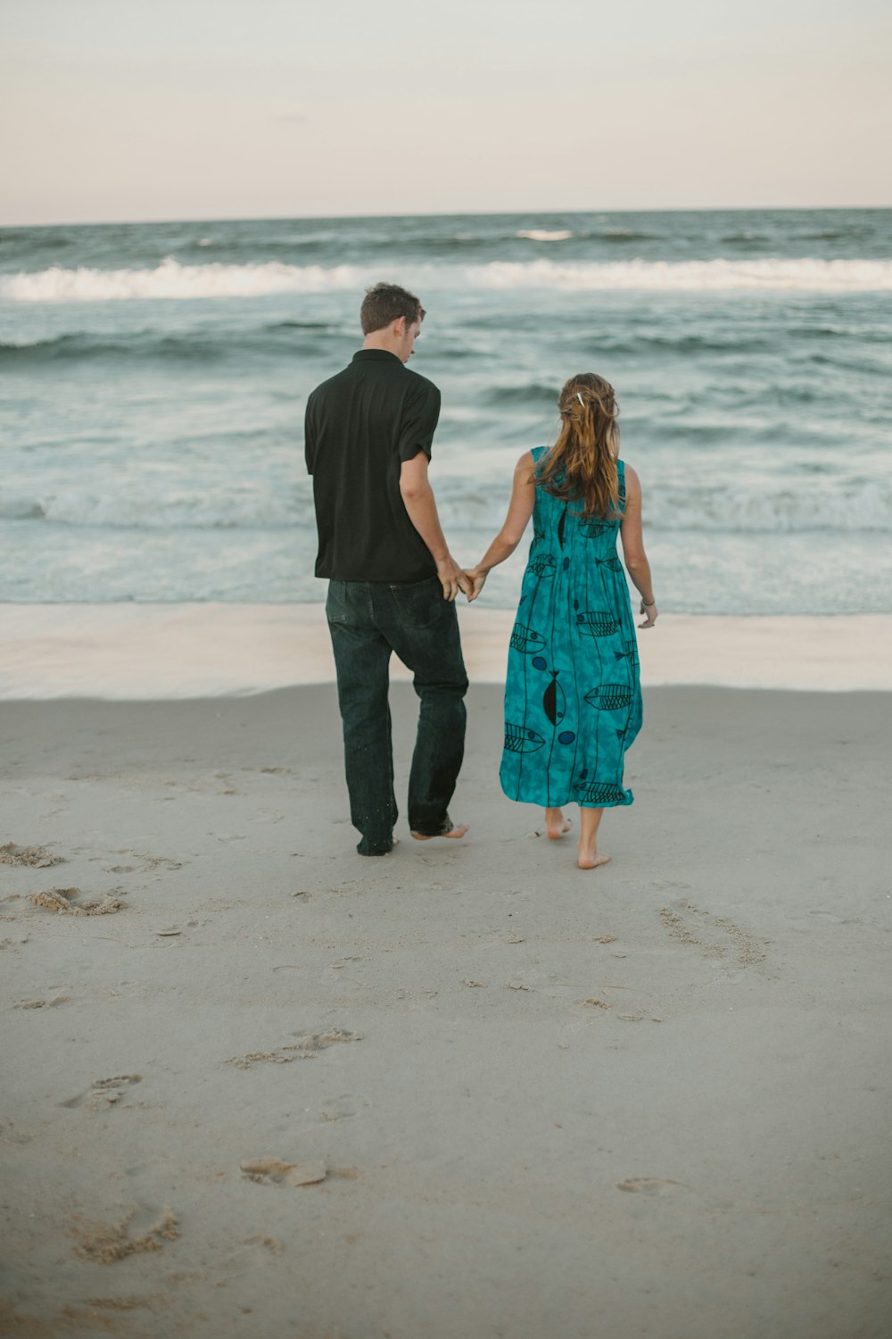hombre y mujer caminando en la playa durante el día