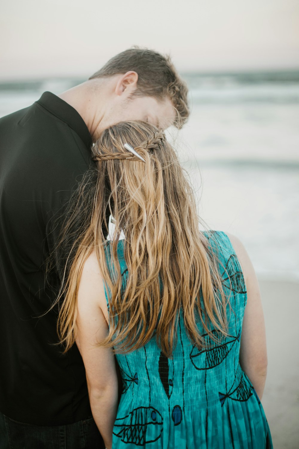 woman in blue sleeveless shirt kissing man in black suit jacket