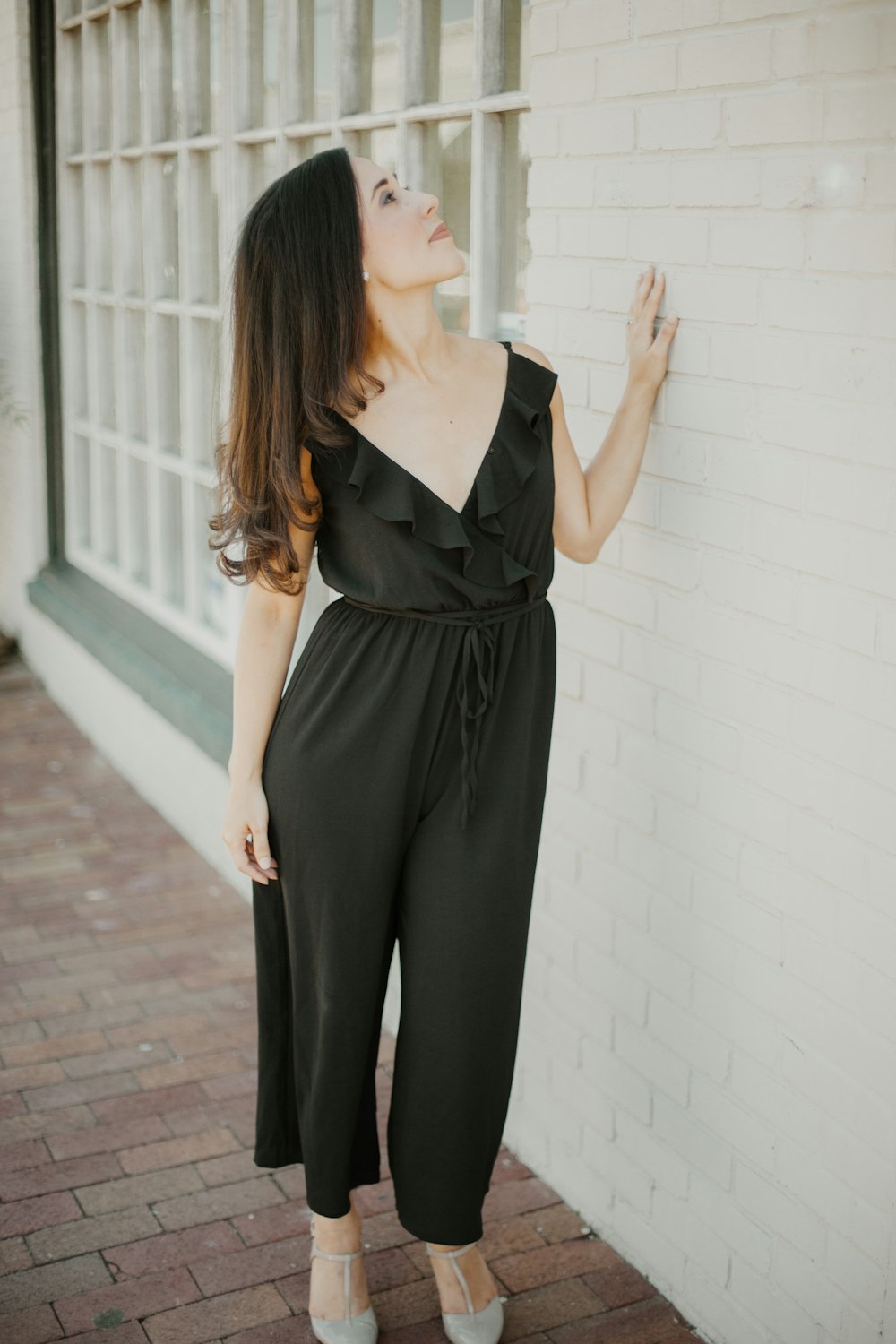 woman in black sleeveless dress standing on brick floor