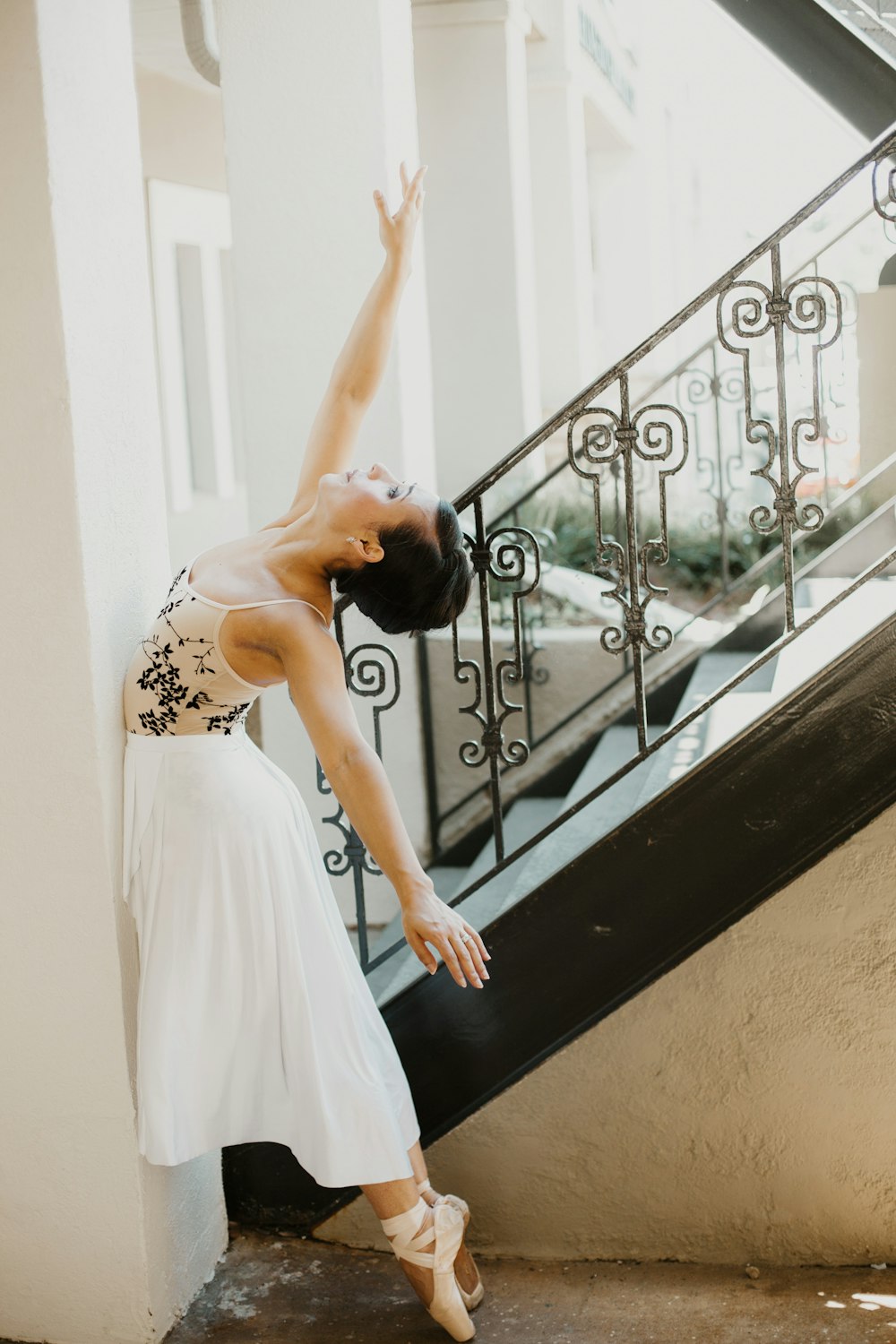 woman in white floral dress leaning on black metal railings