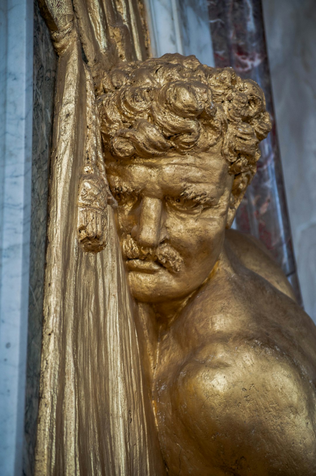 gold statue of man with gold colored chain link