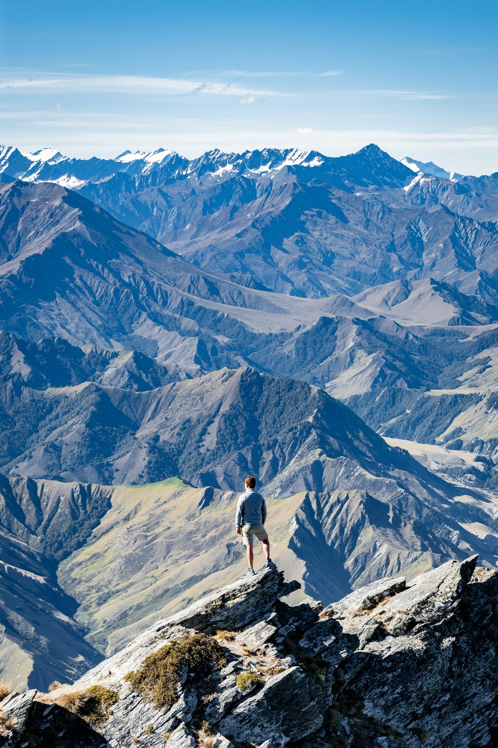 homem na jaqueta preta de pé na montanha de rocha cinzenta durante o dia