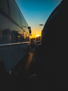 A fleet of buses lined up at a busy urban terminal during sunset.