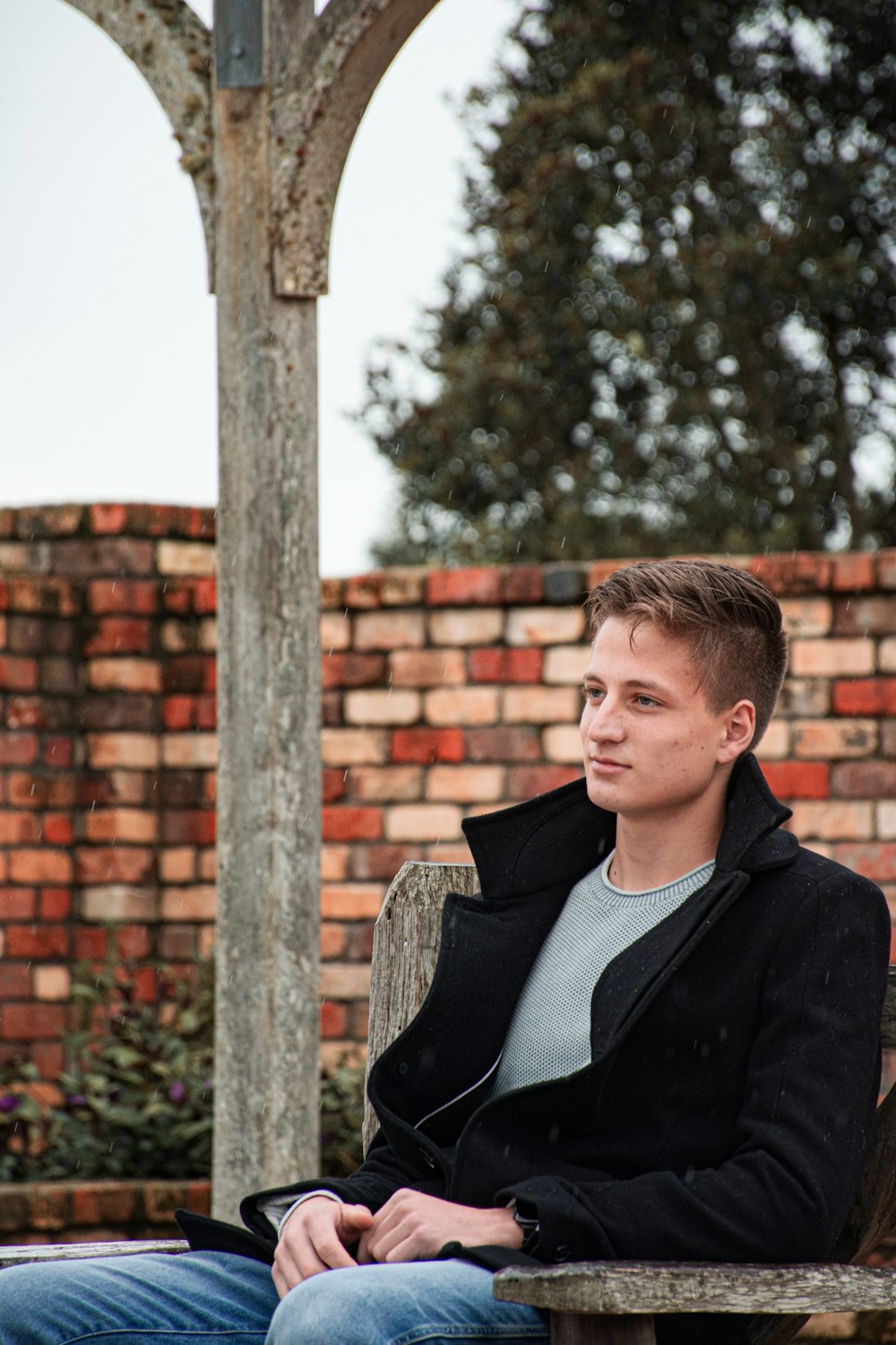 man in black suit jacket standing near brown brick wall during daytime