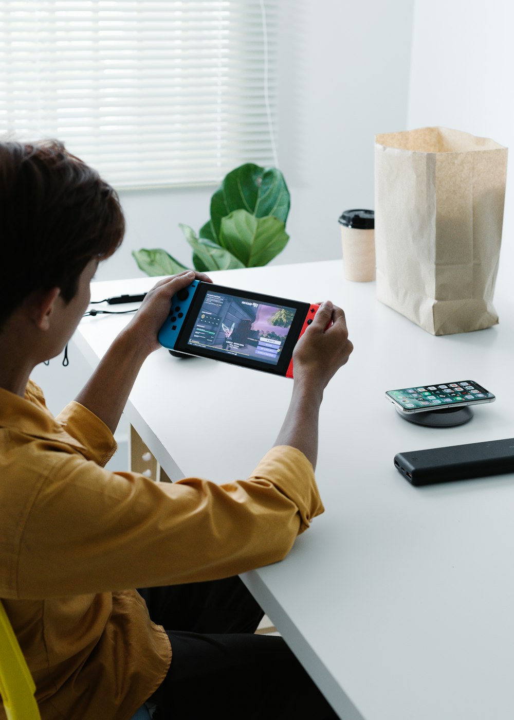 person in yellow long sleeve shirt holding black tablet computer