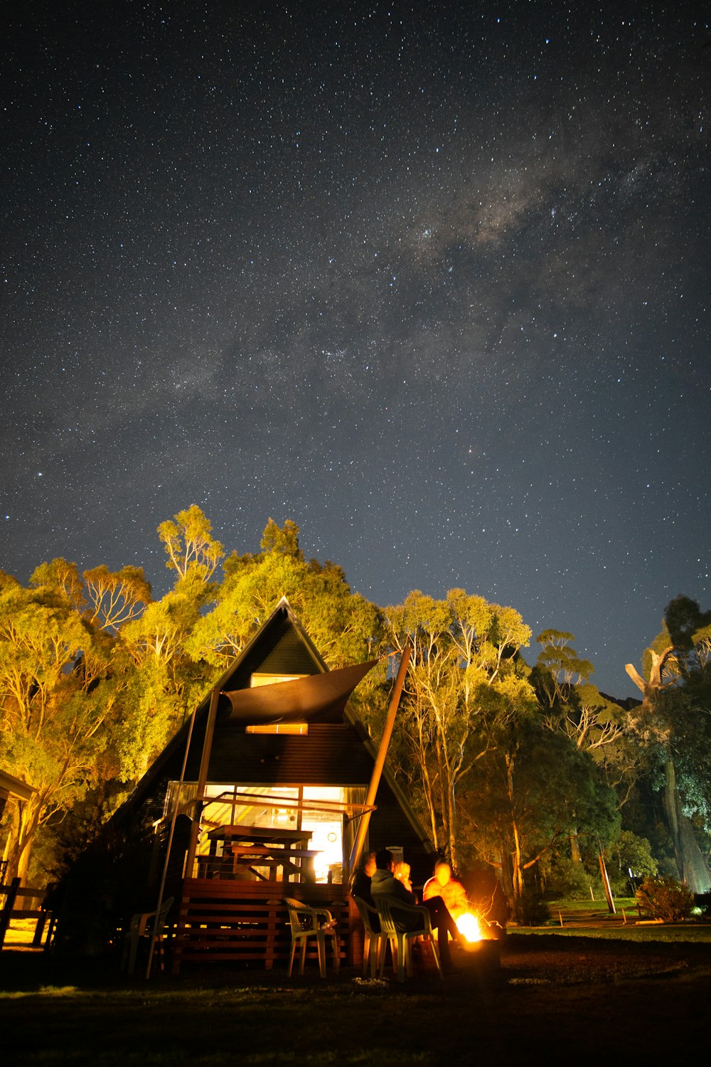 brown wooden house on green grass field under starry night