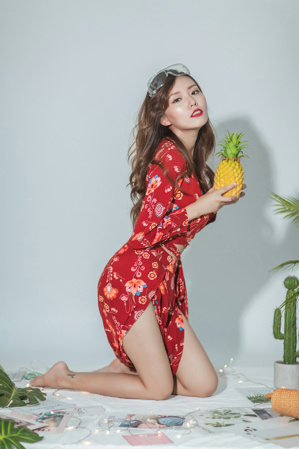 a woman in a red dress holding a pineapple