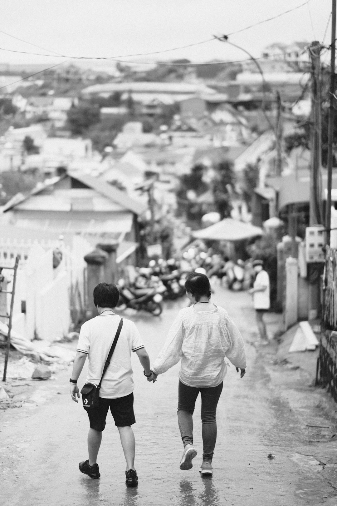 grayscale photo of man in white shirt and black pants walking on street