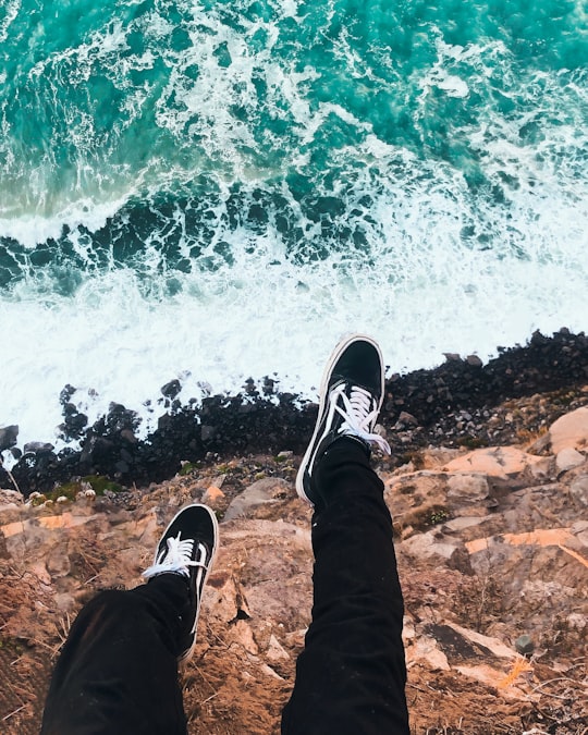 person wearing black and white sneakers in Godley Head New Zealand