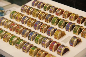 A collection of diverse coin rings displayed on a minimalist white background.