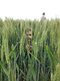 man and woman standing on green grass field during daytime, representing hiding in fear