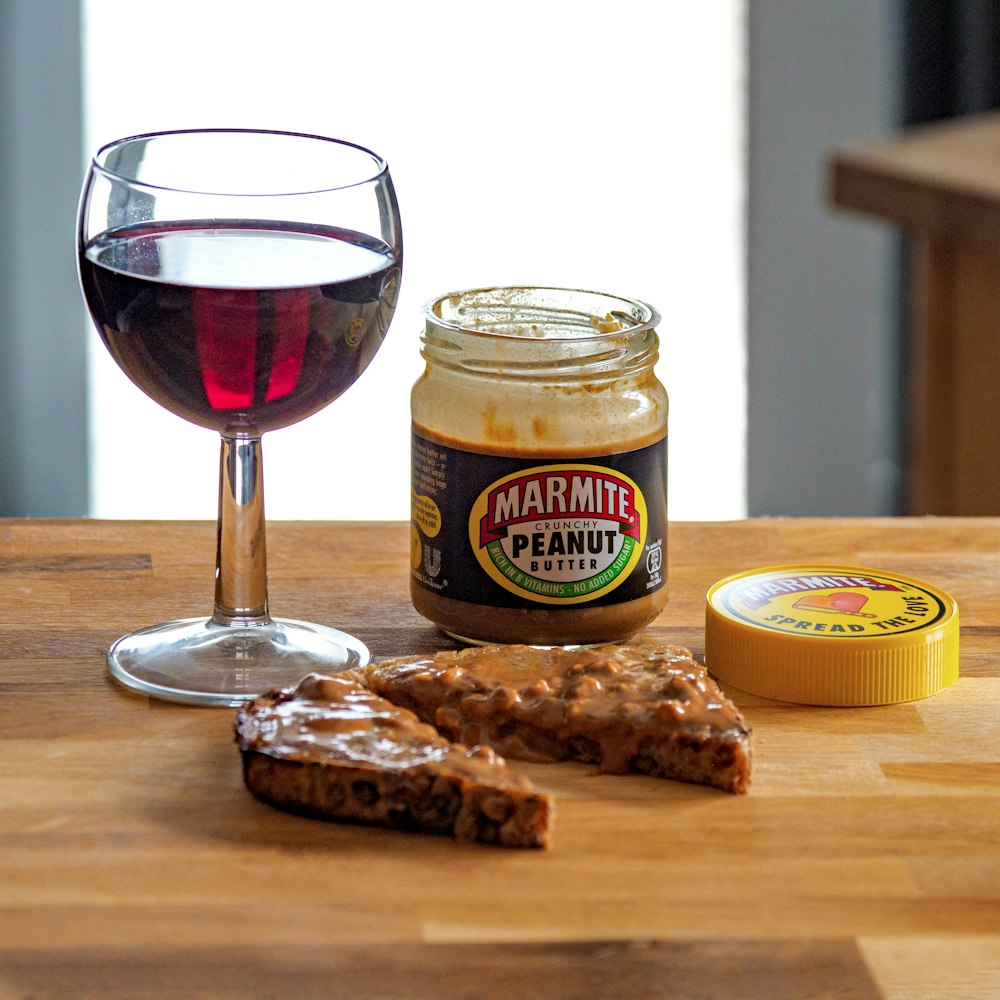 Copa de vino transparente con vino tinto junto a galletas marrones sobre mesa de madera marrón