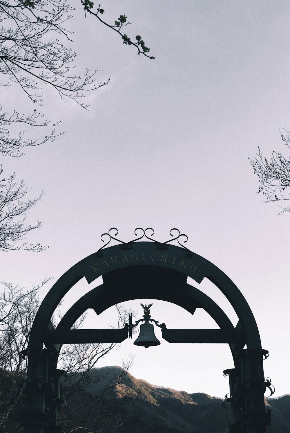 a bell hanging from the side of a wooden arch