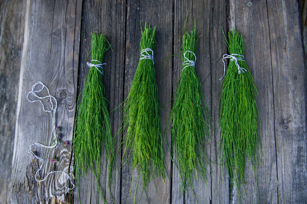 A bundle of natural flour sacks stacked neatly beside a basket of fresh mountain herbs