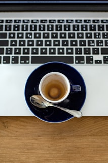 A spilled cup of coffee creating a splash pattern on a laptop keyboard.