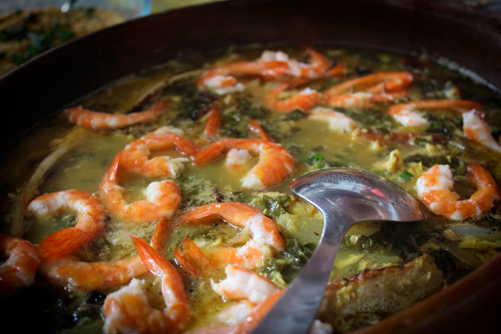 um pote de sopa com camarão e brócolis
