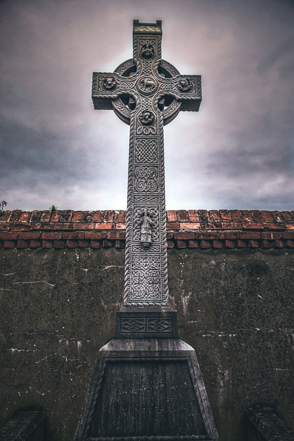 grey cross on brown brick wall