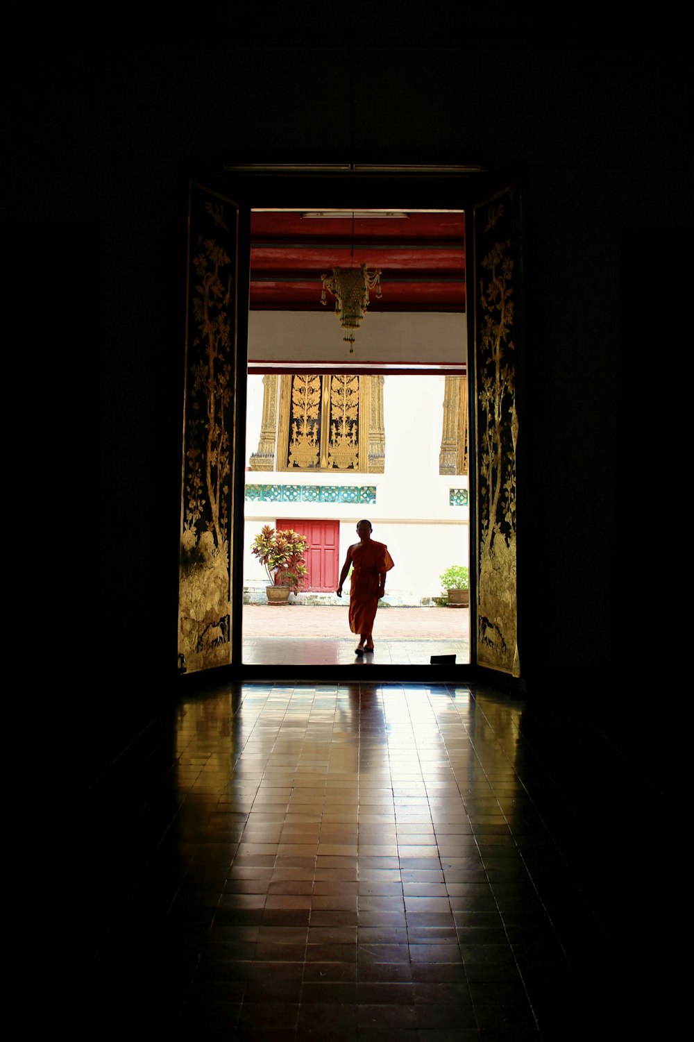 woman in red long sleeve shirt and pants walking on brown wooden floor