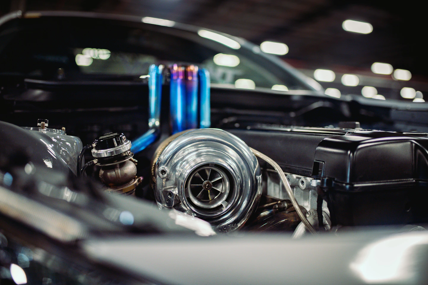 A chrome turbocharger installed in a modified engine bay with custom piping