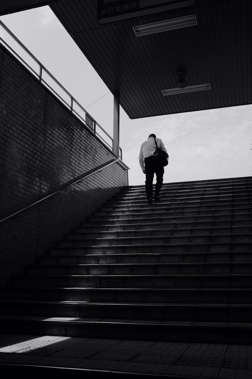 grayscale photo of man walking on stairs