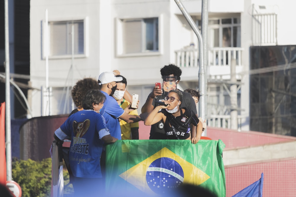 people in blue t-shirt holding blue and yellow surfboard during daytime