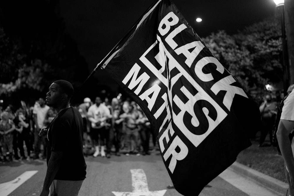 grayscale photo of man holding us a flag