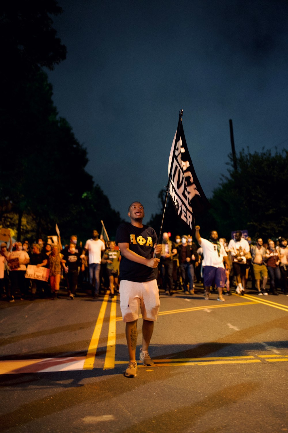 man in black t-shirt and white shorts holding flag