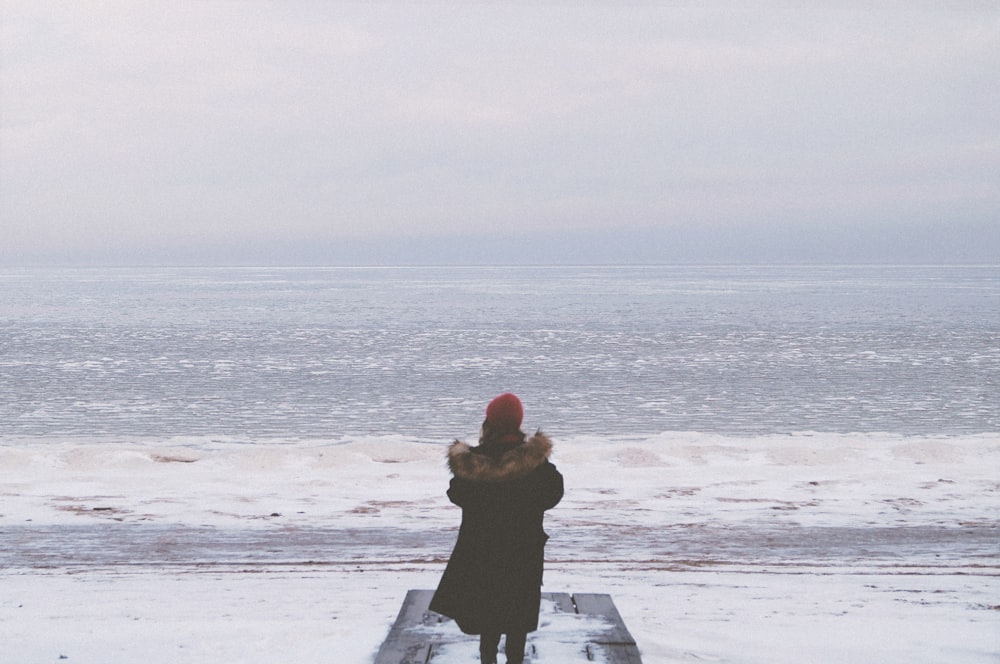 woman in black dress standing on beach during daytime