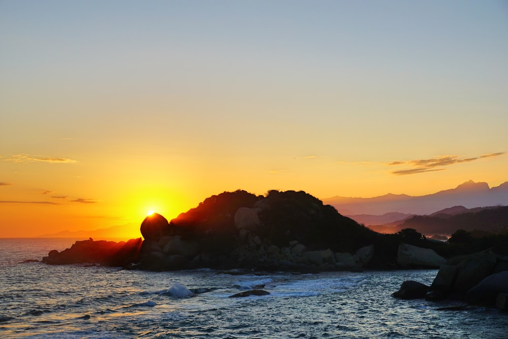 black rock formation on sea during sunset