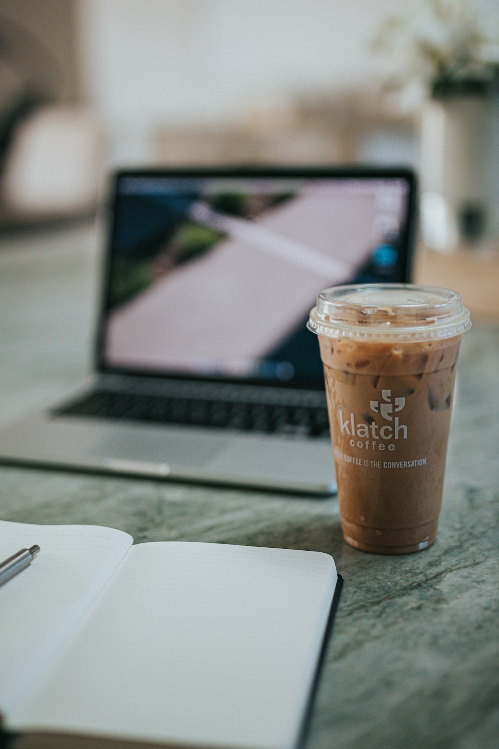 brown and white disposable cup beside macbook pro