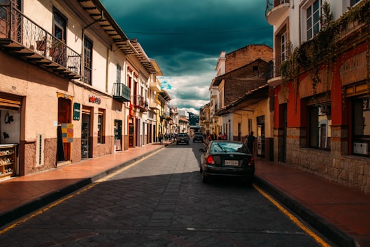 black car parked beside brown concrete building during daytime in Cuenca Ecuador