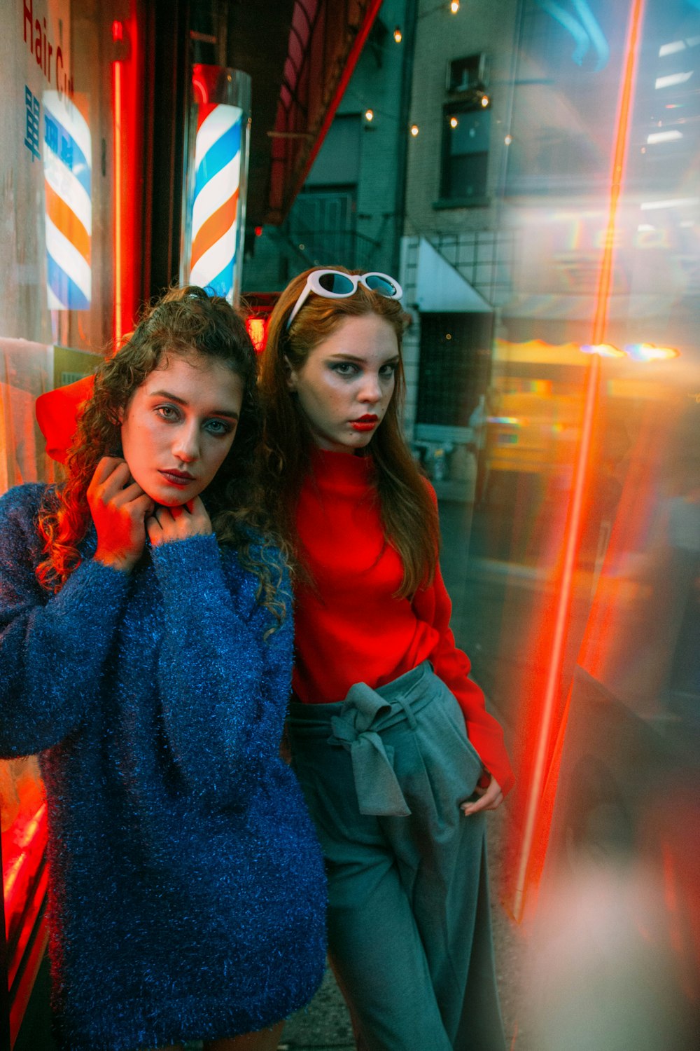 2 women smiling in front of glass wall