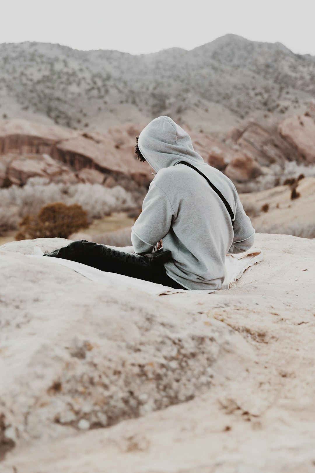 person in gray hoodie sitting on rock