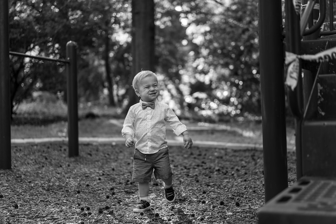 grayscale photo of child in white long sleeve shirt and pants standing on ground