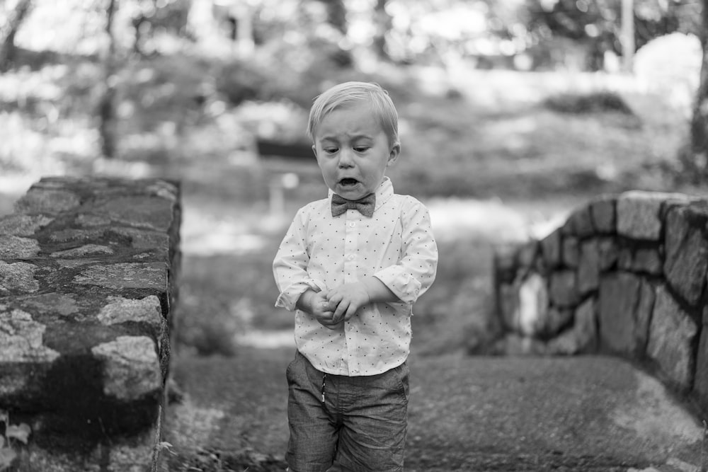 grayscale photo of boy in dress shirt and black pants