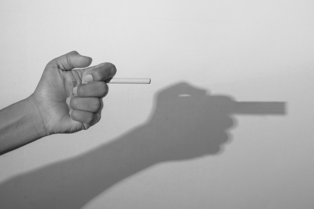 grayscale photo of person holding cigarette stick