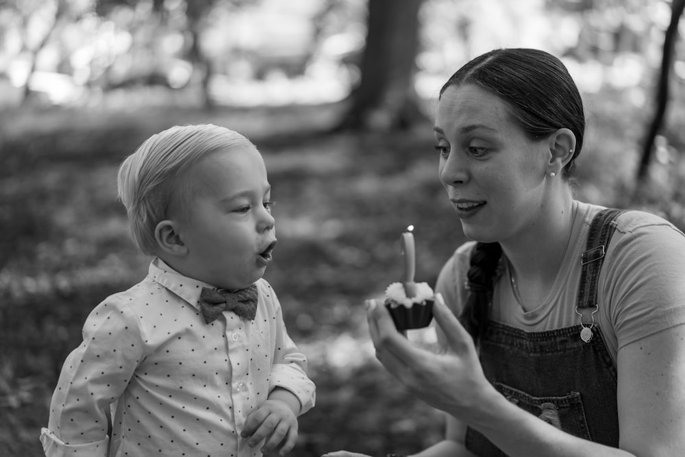 grayscale photo of girl in button up shirt holding lollipop