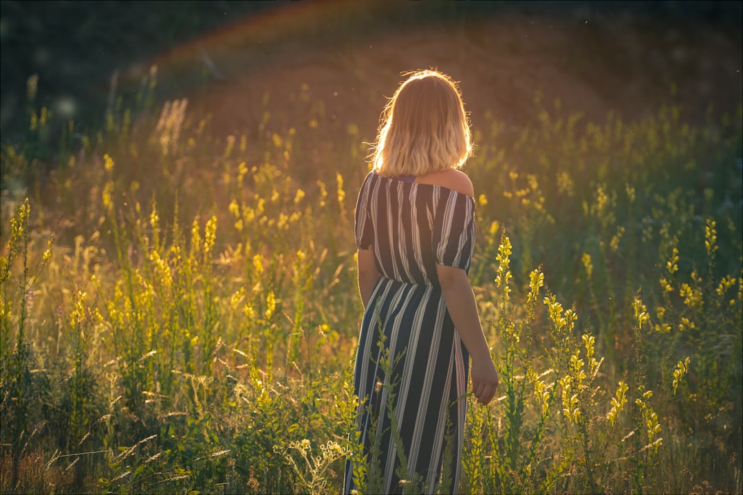 woman in black and white stripe dress standing on green grass field during daytime