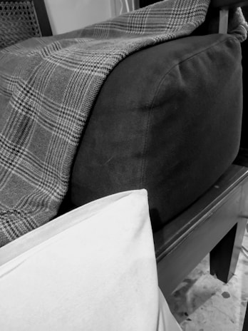 Close-up of a bright, patterned throw blanket draped over a modern sofa in a sunlit living room.