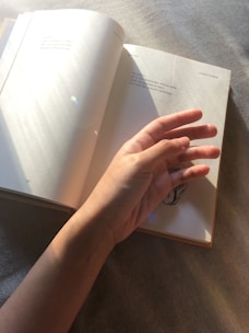 Close-up of hands holding an open book with golden light filtering through, evoking calm and inspiration.